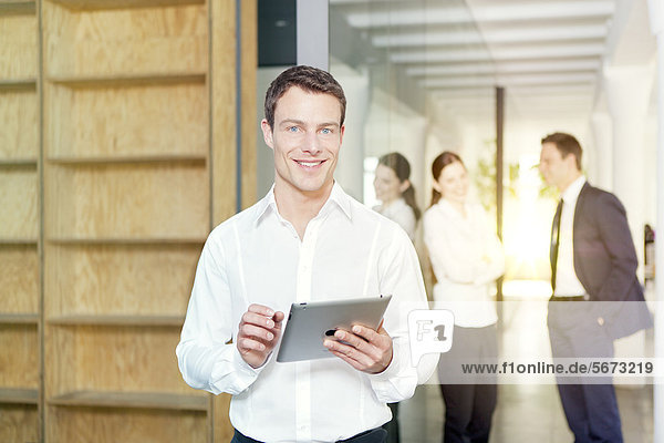 Smiling businessman with tablet PC in office