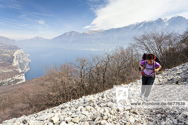 Hiker during the ascent from Campione to Madonnina di Monte Castello  ovrlooking Lake Garda and the village of Malcesine  Brescia  Italy  Europe