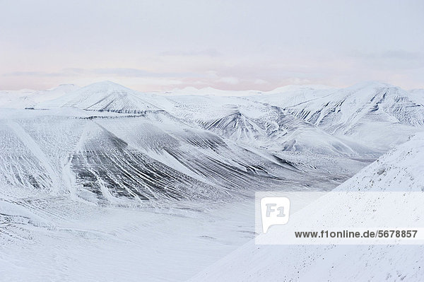 Pastellfarbenes Licht am Horizont über schneebedeckter Berglandschaft zu Beginn der Polarnacht  Spitzbergen  Svalbard  Norwegen  Europa