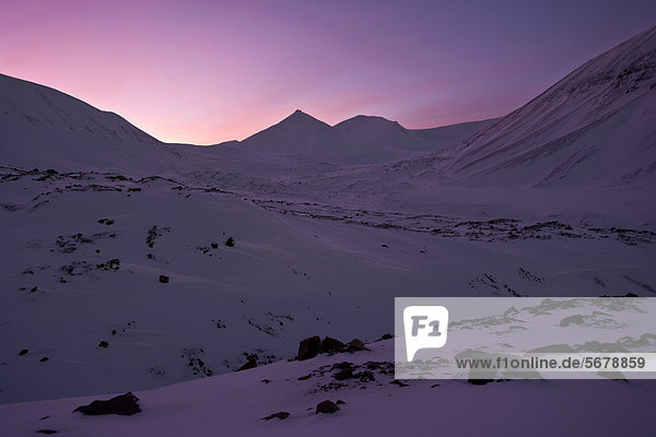 Lichtstimmung der Polarnacht  pinkfarbener Himmel vor schneebedeckter Kulisse einer steinigen Gletscherlandschaft  Spitzbergen  Svalbard  Norwegen  Europa
