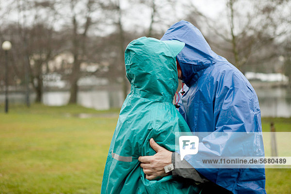 Senior couple in waterproof clothing kissing in park