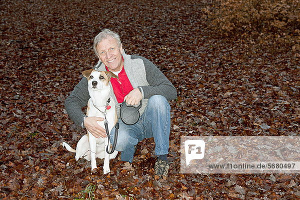 Portrait of senior man with dog in forest