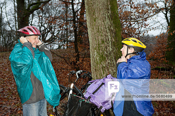 Senior couple preparing to cycle in forest
