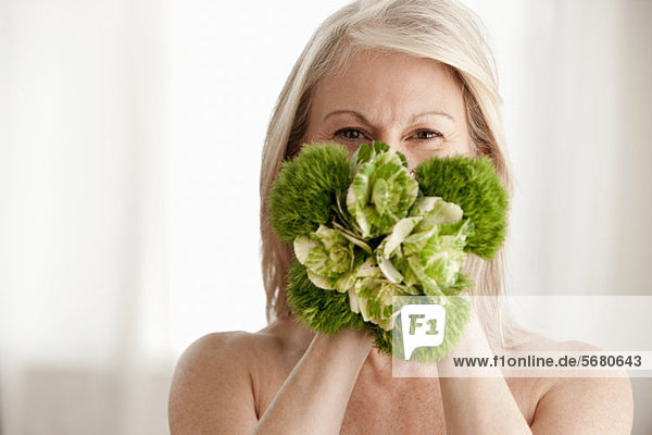 Reife Frau hält Pflanze  Portrait