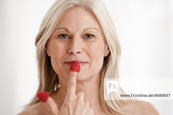 Mature woman wearing raspberries on fingers  portrait