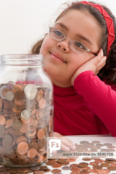 Junges Mädchen mit einem Glas voller Münzen