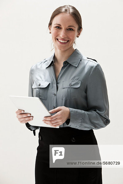 Portrait einer jungen Geschäftsfrau lächelnd und mit digitalem Tablett  Studioaufnahme