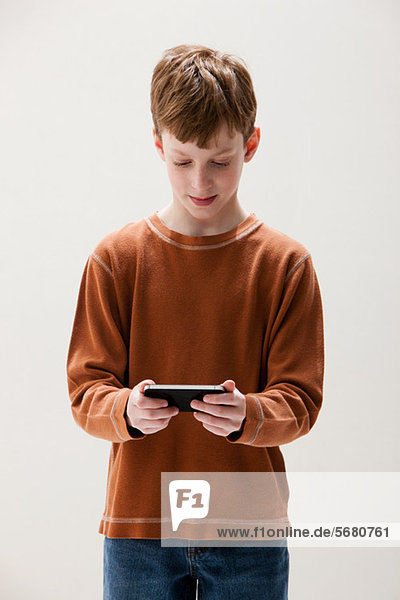 Junge in braunem Pullover spielt Handheld-Videospiel  Studioaufnahme