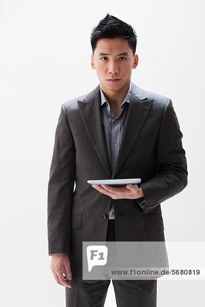 Young Asian businessman holding digital tablet  studio shot