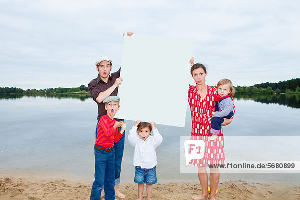 Family by lake  holding a blank sign
