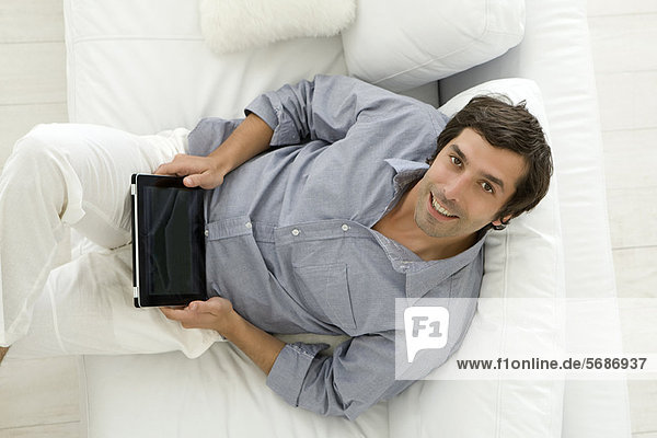 Man using tablet computer on sofa