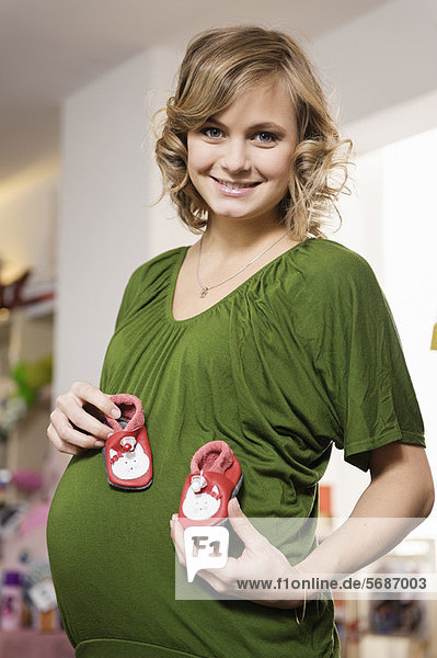 Schwangere Frau kauft Babyschuhe