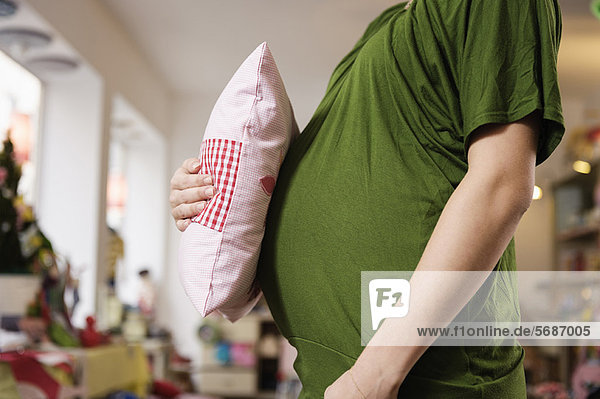 Schwangere Frau mit Kissen am Bauch