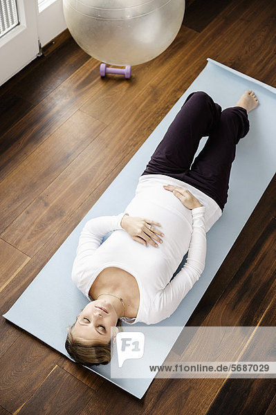 Schwangere Frau beim Yoga auf der Matte