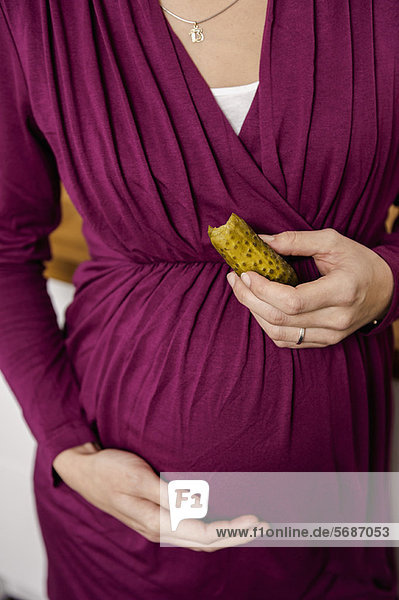 Schwangere Frau isst Essiggurke