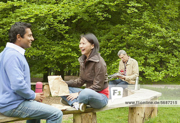 Couple talking on wooden bench in park