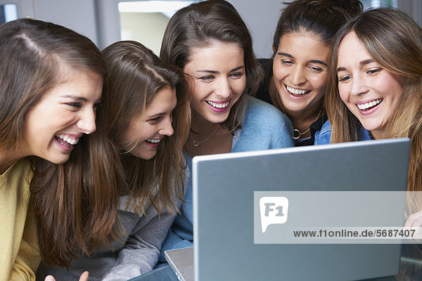 Smiling women using laptop together