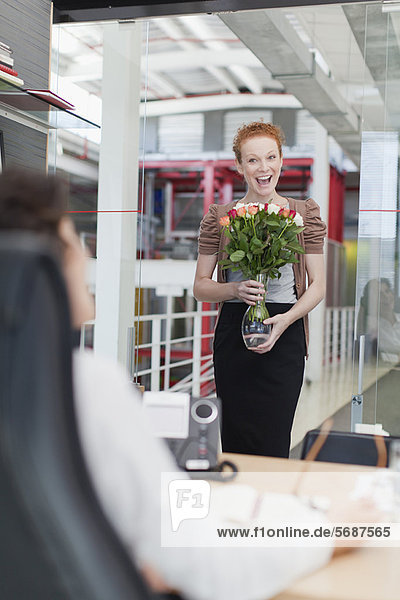 Businesswoman carrying vase of flowers