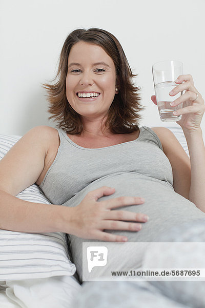 Frau mit schwangeren Bauch auf dem Bett