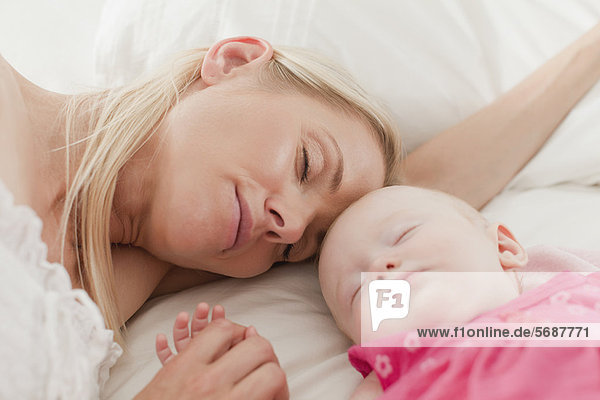 Mother and baby sleeping on bed