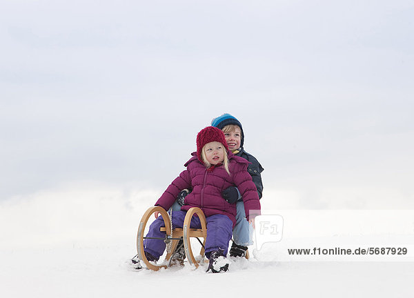 Children sitting on sled in snow