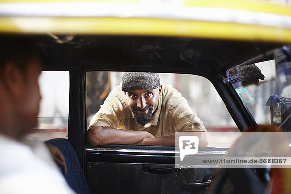 Lächelnder Mann  der sich im Taxifenster lehnt
