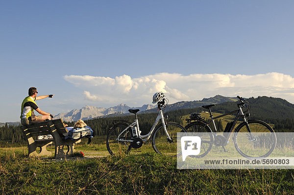 Couple with electric bicycles  taking a break on the Winklmoosalm alp  Reit im Winkl  Chiemgau  Upper Bavaria  Bavaria  Germany  Europe