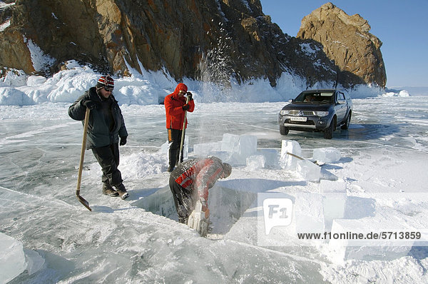 Mann sägt ein Loch ins Eis  Vorbereitungen fürs Eistauchen  Baikalsee  Insel Olchon  Sibirien  Russland  Eurasien
