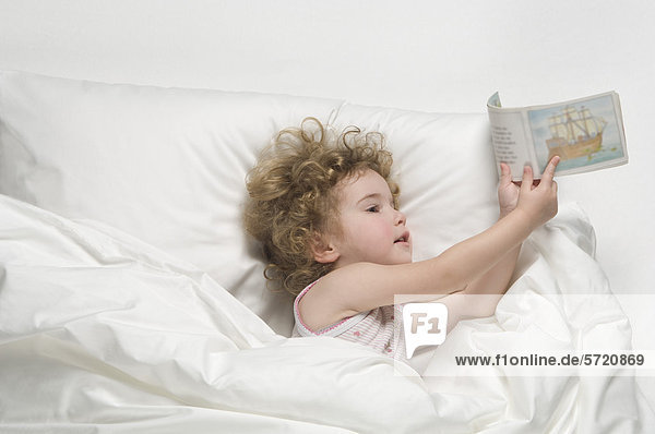Mädchen auf dem Bett liegend mit Buch
