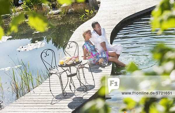 Austria  Salzburg County  Couple having breakfast on bridge over pond