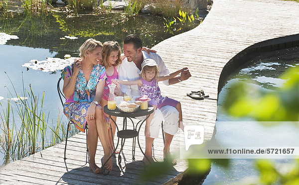 Austria  Salzburg County  Family having breakfast on bridge over pond