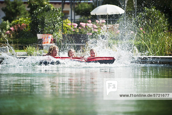 Österreich Salzburger Land Familie auf Luftmatratze im Naturbad