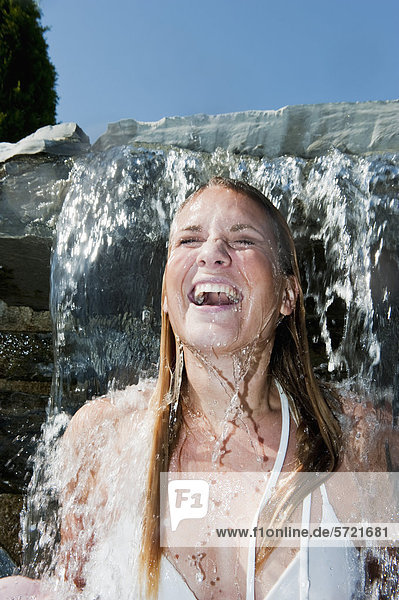 Österreich  Salzburger Land  Junge Frau unter Wasserfall