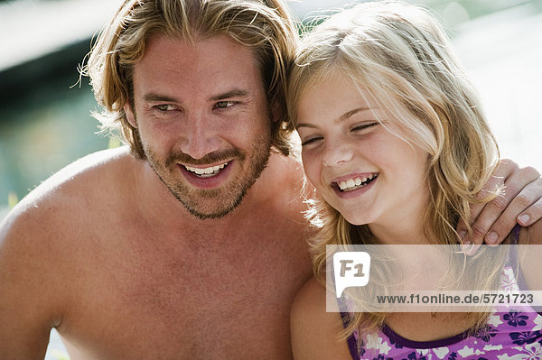 Österreich  Salzburger Land  Vater und Tochter am Pool sitzend