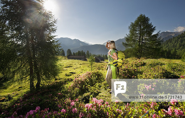 Österreich  Salzburger Land  Junge Frau auf der Alm stehend und Landschaft beobachtend