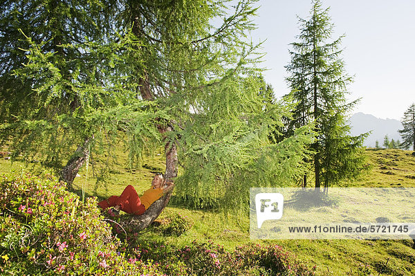 Österreich  Salzburger Land  Junge Frau am Baum auf der Alm