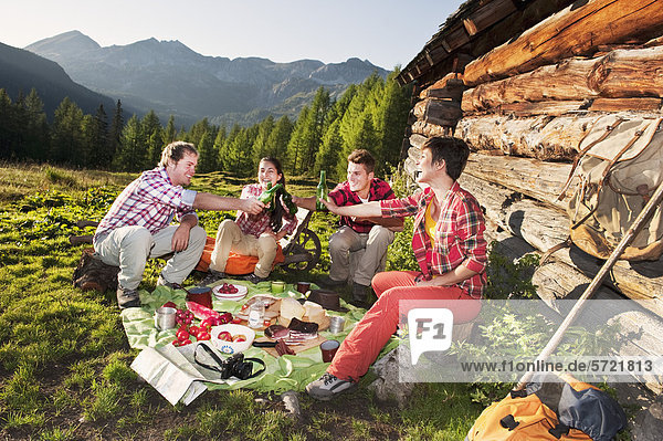 Austria  Salzburg  Men and women having picnic near alpine hut at sunset