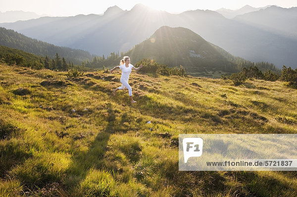 Österreich  Salzburger Land  Junge Frau beim Laufen auf der Alm