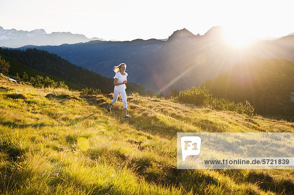 Österreich  Salzburger Land  Junge Frau beim Laufen auf der Alm