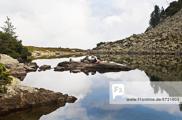Österreich  Steiermark  Mann und Frau liegen auf Felsen am Spiegelsee