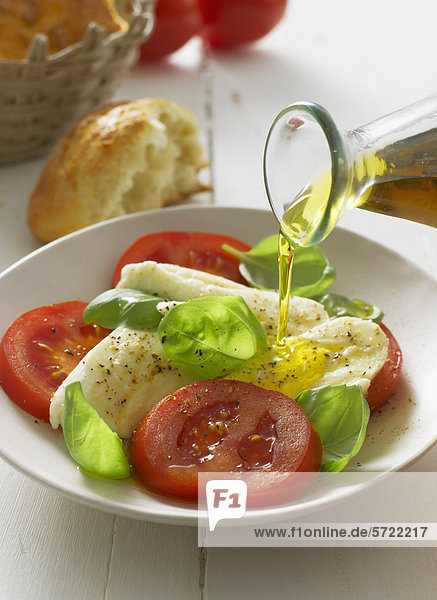 Olivenöl auf Caprese-Salat im Teller  Nahaufnahme