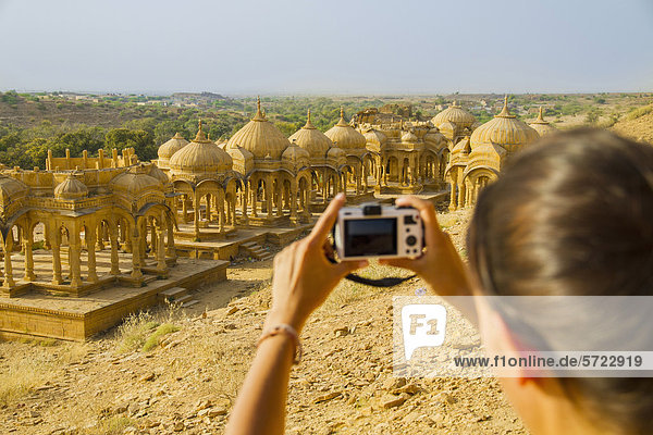 India  Rajasthan Jaisalmer  Female tourist photographing at Bada Bagh Cenotaphs