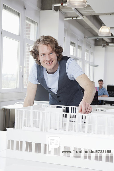 Germany  Bavaria  Munich  Architect with architectural model  colleagues working in background