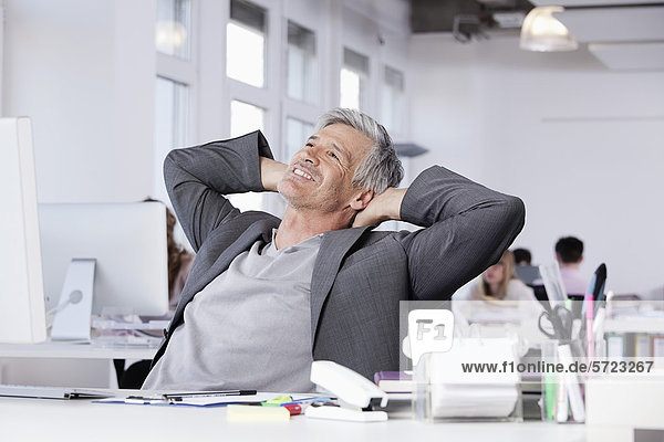 Mature man smiling  colleagues working in background