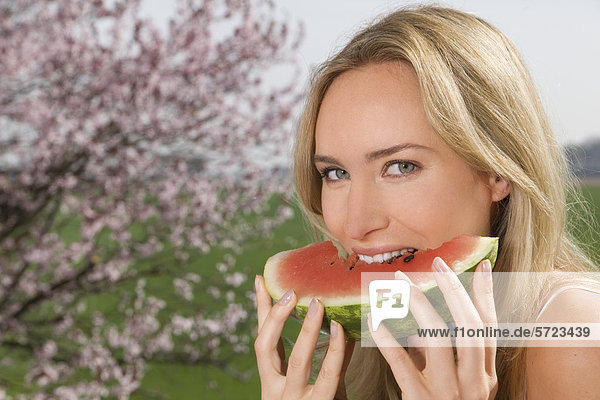 Deutschland  Nordrhein-Westfalen  Junge Frau isst Wassermelone  lächelnd  Portrait