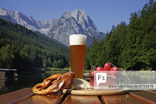 Deutschland  Oberbayern  Bayerische Snacks auf dem Tisch  Berg mit See im Hintergrund