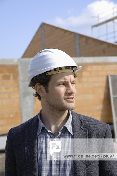 Junger Mann mit Schutzhelm auf der Baustelle stehend