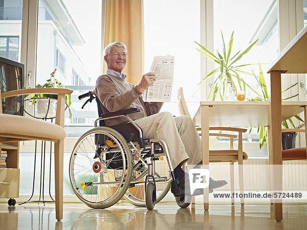 Älterer Mann liest Zeitung im Rollstuhl