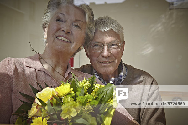 Deutschland  Köln  Seniorenpaar mit Blumenstrauß  lächelnd