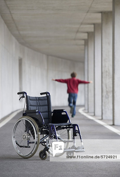 Österreich  Mondsee  Junger Mann beim Balancieren mit Rollstuhl im Vordergrund